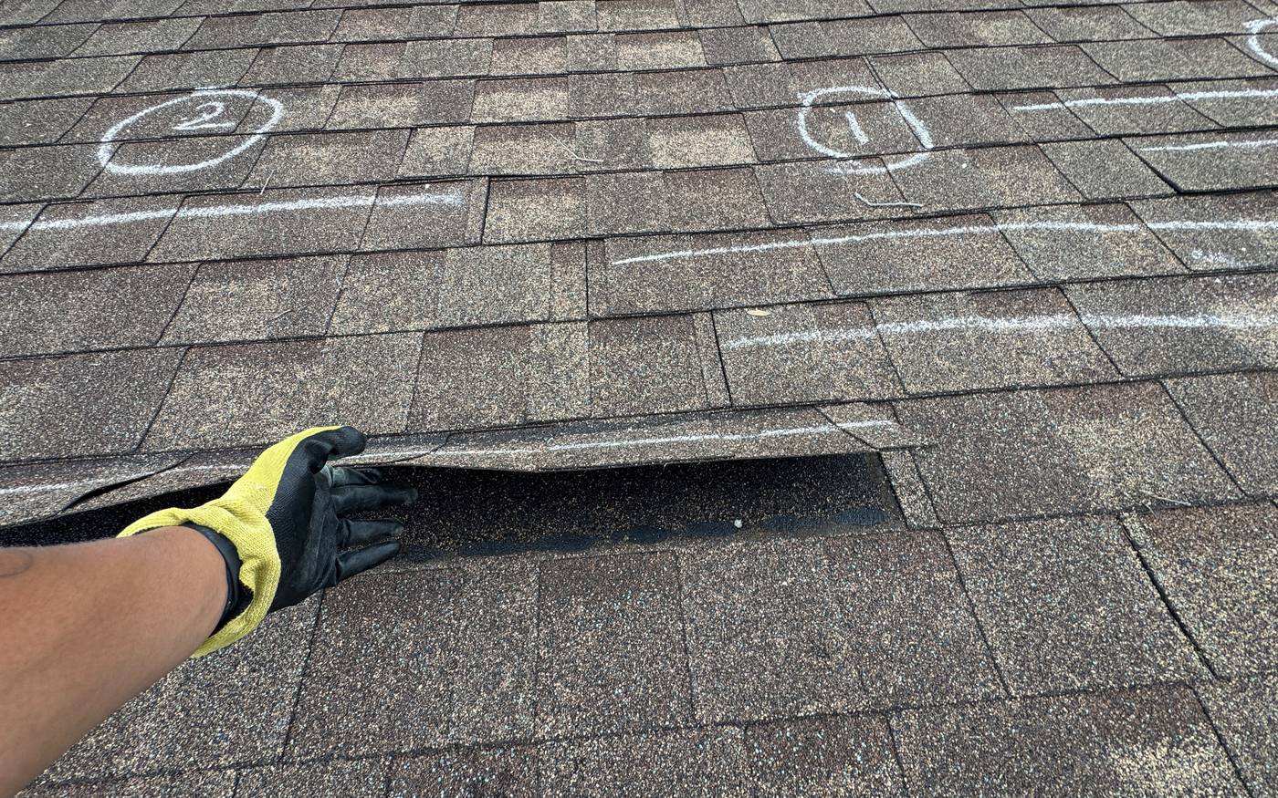 Everest technician lifting a damaged shingle during a roof inspection in Tampa, FL